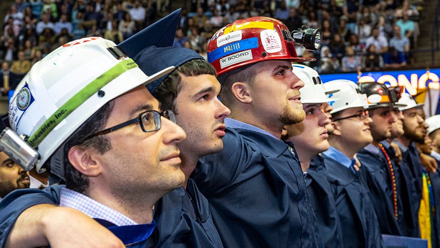Graduates wearing hard hats at graduation.