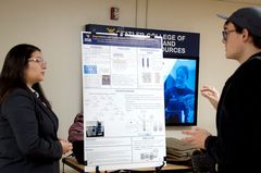 Female student presenting poster to grad student.