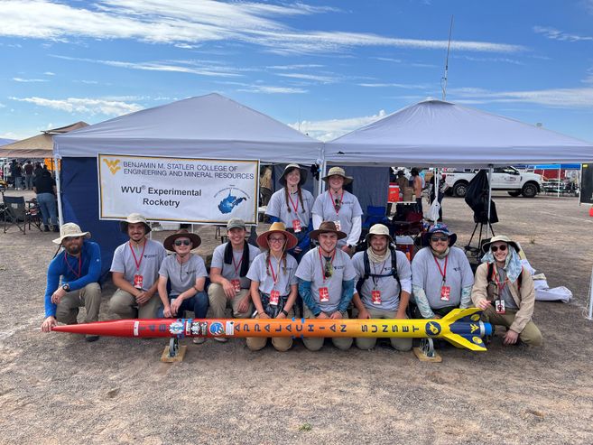 2022 WVU Rocketry Team in the desert posing with their rocket, the Appalachin Sunset.