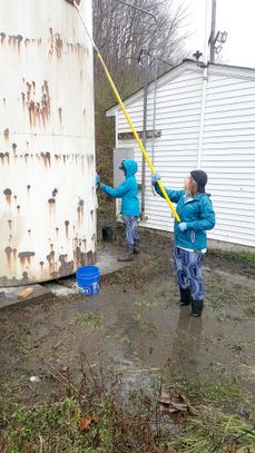 A photo of two EWB members standing in knee-deep water cleaning a tank.