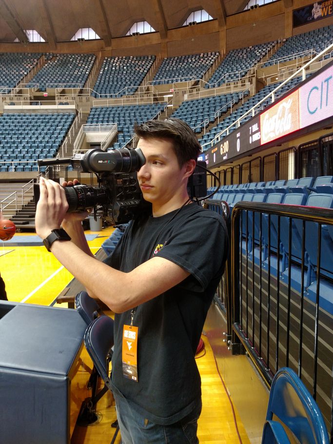Trevor Gromen holding a shoulder camera at the WVU Coliseum. 