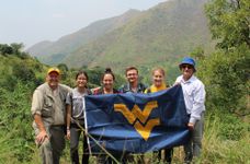 Members from WVU Engineers Without Borders hold a WVU flag in the mountains of Uganda 