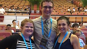 Andy Maloney, Emily Phipps and Katie O'Connell pose together inside an auditorium at the Global Grand Challenges Summit in Bejing, China.