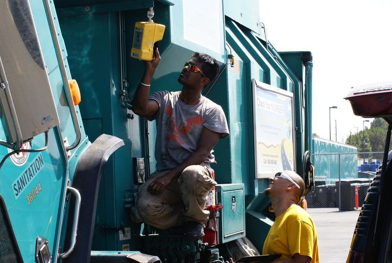Arvind Thiruvengadam (left) and Saroj Pradhan (right) check for leaks in the natural gas fuel system of a refuse truck. 
