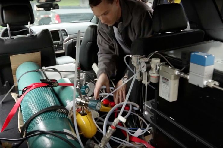 A photo of Marc Besch installing equipment in a car engine.