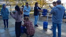 Engineering students outside participating in a hand pump competition using buckets, pipes, and tools. 