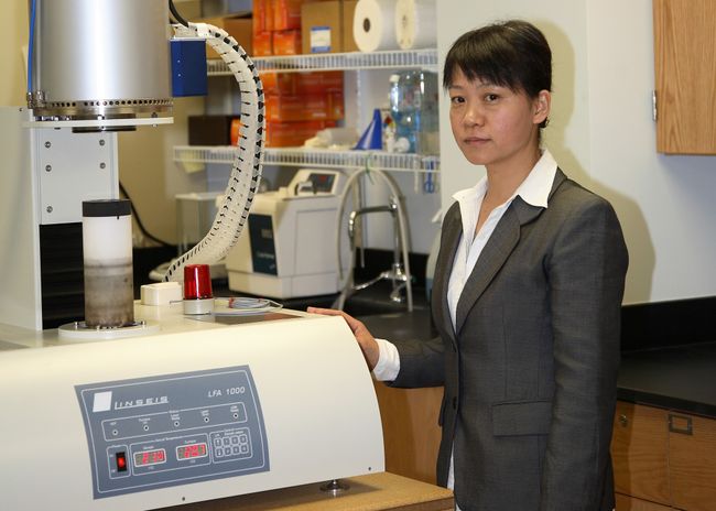 A portrait of Xueyan Song behind a piece of lab equipment.