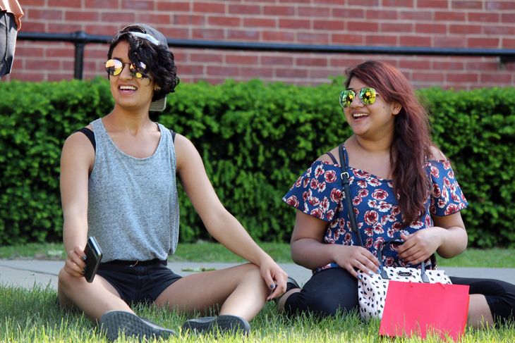 Sofia Lateef laughs with friends while sitting on campus in Woodburn Circle.