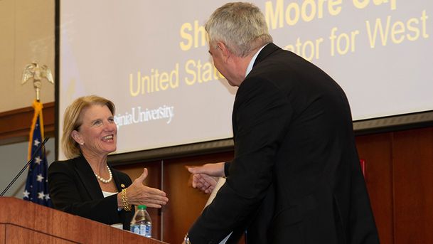 Senator Shelley Moore Capito shakes hands with a man in front of podium. 