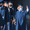 Student wearing face mask gives thumbs-up at graduation