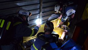 Mine safety volunteers practice a medical evacuation procedure by placing a dummy on to a cot to be carried out of the mine