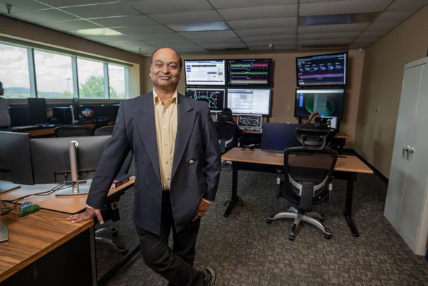 Anurag Srivastava stands in a computer lab in front of several computer monitors. 