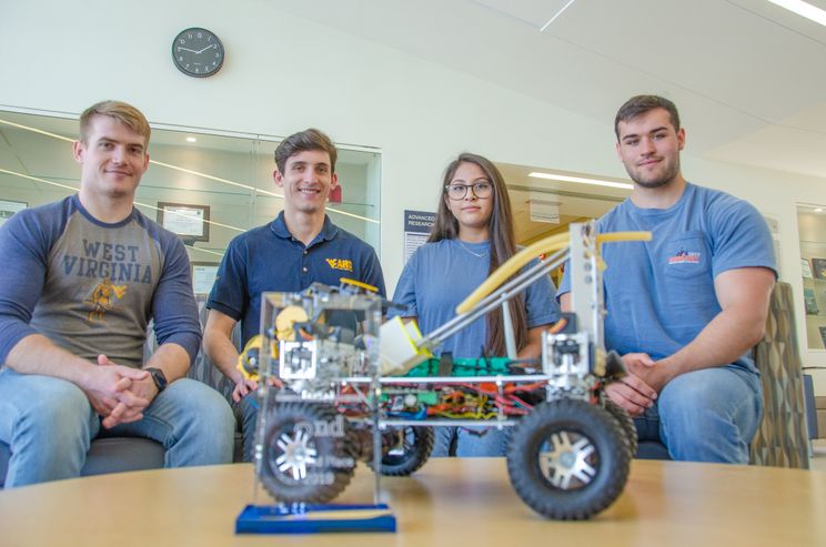 A photo of four students with a robot.