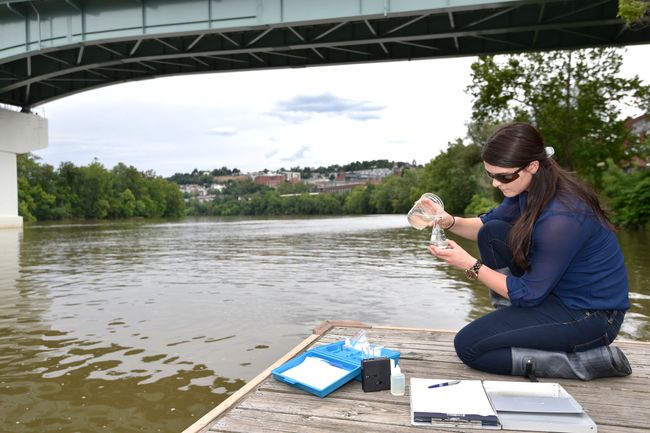 A woman takes water samples from the Mon River in Morgantown.