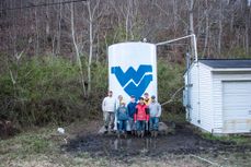 A photo of EWB members standing by a water tank with a Flying WV painted on it.
